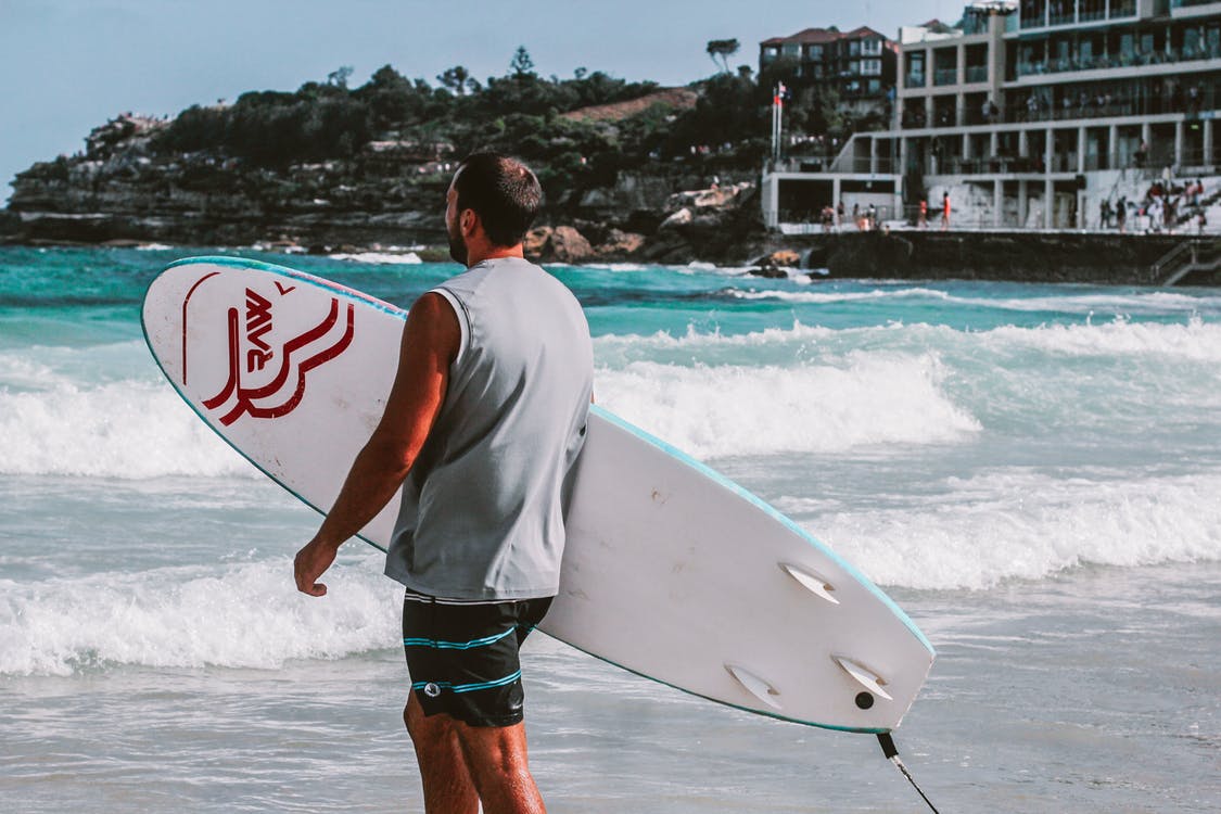 Mann mit Surfbrett vor Wasser